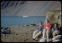 Image of Three Eskimos [Inuit] by tent, the Bowdoin in distance