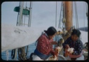 Image of Eskimo [Inuk] woman and Inawahoo eating meat, on board