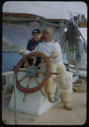Image of Miriam MacMillan and Eskimo [Inuk] man with glasses, at wheel