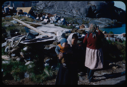 Image of Two Eskimo [Inuit] women and a child; barrel dump beyond