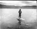 Image of Eskimo [Inuk] man standing on dead walrus